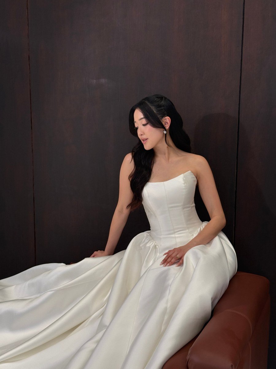 Bride in a strapless satin gown seated against dark timber panelling